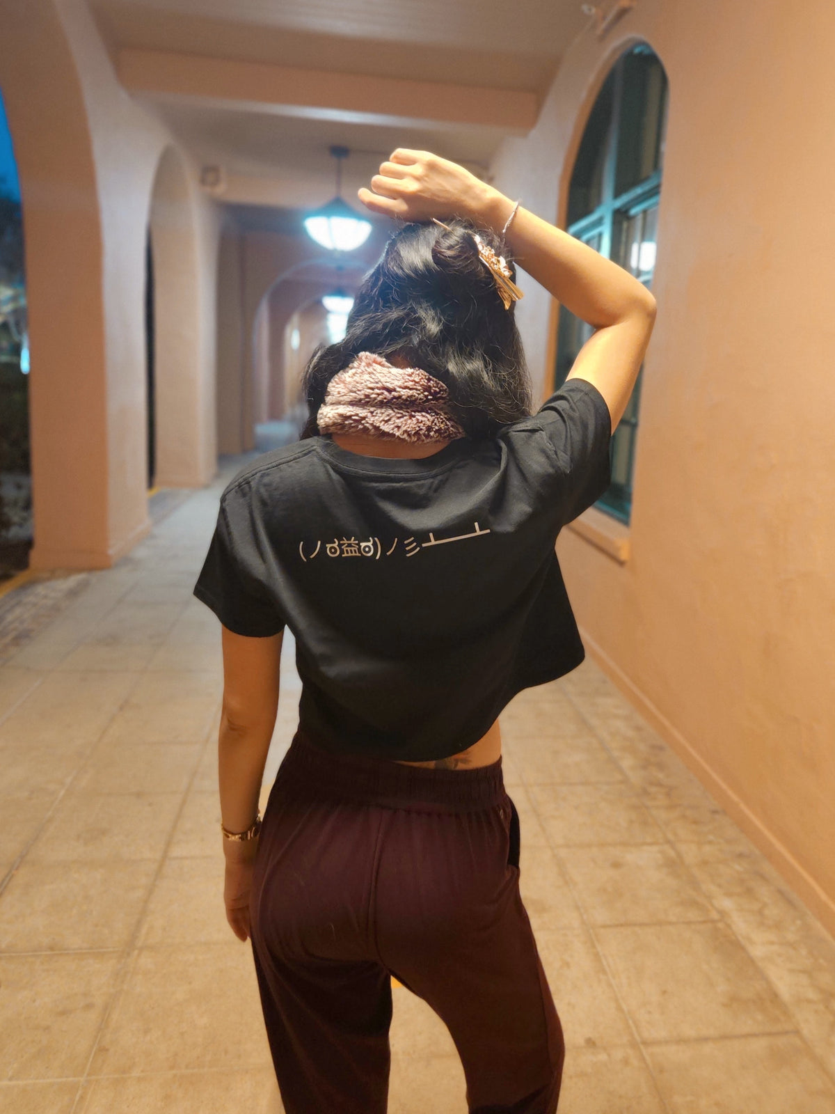 Table Flip Emoticon Crop Top worn by female model in a sandy-colored hallway